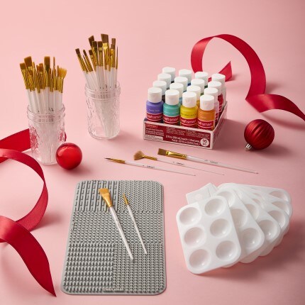 Paint brushes and supplies on pink background