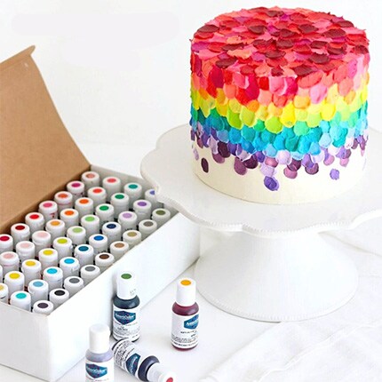 box of gel food coloring next to cake with rainbow icing decorations