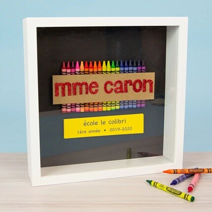 Boîtes à ombre blanches avec des crayons et le nom de l'enseignant.