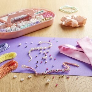 A jewelry kit on a table with bracelets in the process of being made