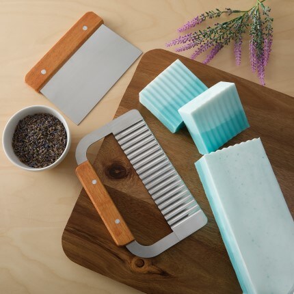 DIY blue soap cut into two pieces on wooden board with two soap cutters 