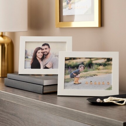 two white frames on table with family photos