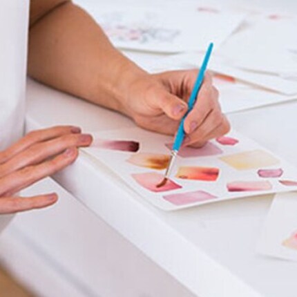 A pair of hands painting watercolors.