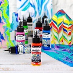 paint marbling canvas with various paint bottles