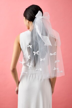 back of woman wearing a while tulle veil with white ribbon bows