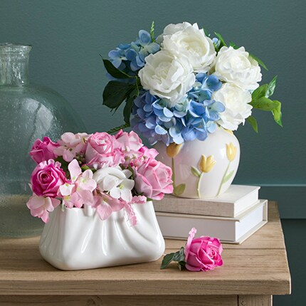 white ceramic purse with pink flowers and white tulip vase with blue and white faux florals