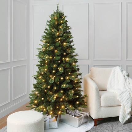 A Christmas tree with lights and presents in a room