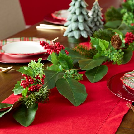 A greenery garland with red runner on table. 