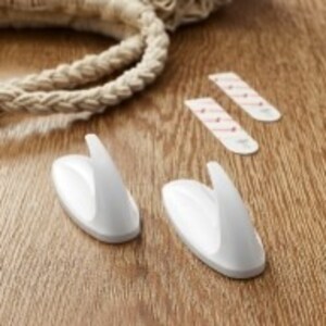 A pair of white command Hooks on a wooden surface