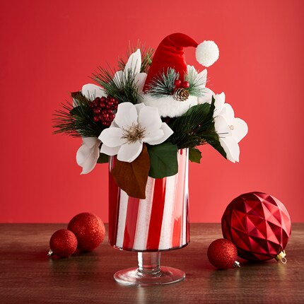 A glass container with white poinsettias and ornaments