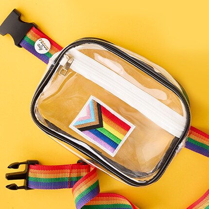 Clear rectangular fanny pack with a white zipper and black trim, featuring a Progress Pride flag patch on the front. 