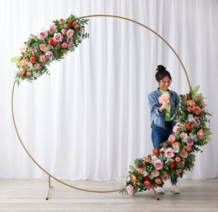 woman placing flowers in gold circle arch