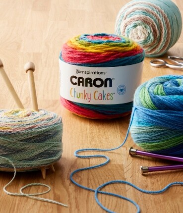 Pelotes de fil Caron Cakes sur une table en bois.