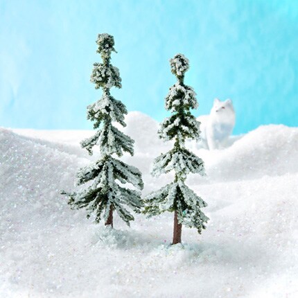 two miniature snow-covered trees with snow fox
