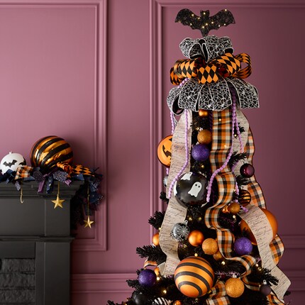 Black Christmas tree decorated with black, orange, and purple ornaments, including striped and checkered balls, ghost figures, and a bat topper.