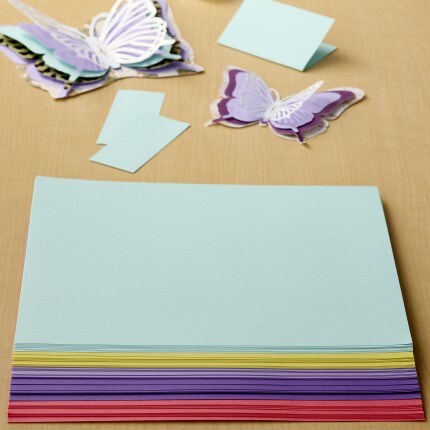 assorted stack of recollections cardstock paper with purple and blue paper butterflies all sitting on a wooden table 