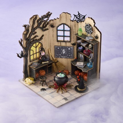 miniature halloween witch room diorama with cauldron, potions, pumpkins, and spooky decorations with purple hazy background