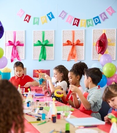 kids crafting at table in room decorated for birthday party