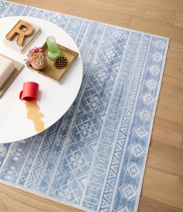 blue patterned rug underneath table with food and spilled drink