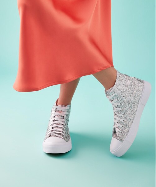 A woman wearing a skirt and sneakers.