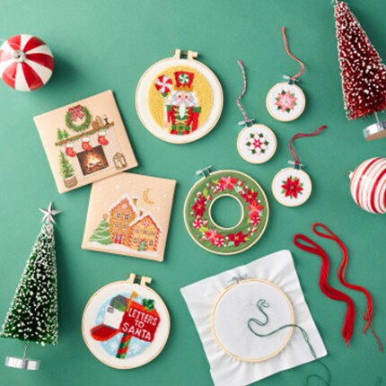 Christmas cross stitch with Santa and Christmas Trees on a table with thread