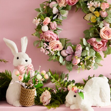 white Easter bunny decorations underneath pink and green wreath