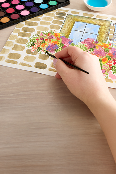 A pair of hands paints with watercolors