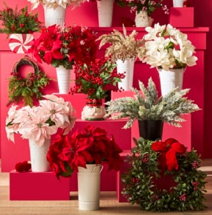 red and pink poinsettias, white magnolias and ever green faux plants in white vases on red blocks