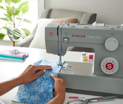 hands using Singer sewing machine with blue cloth