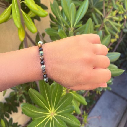MindYourBiz bracelet on a person with a leafy green background