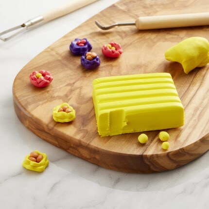 Yellow clay sitting on wooden table with pre made flowers around it