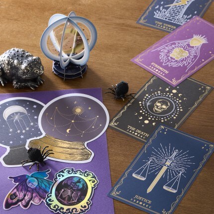 halloween themed papercraft display with tarot cards, crystal ball, faux spiders and a decorative toad on a wooden table