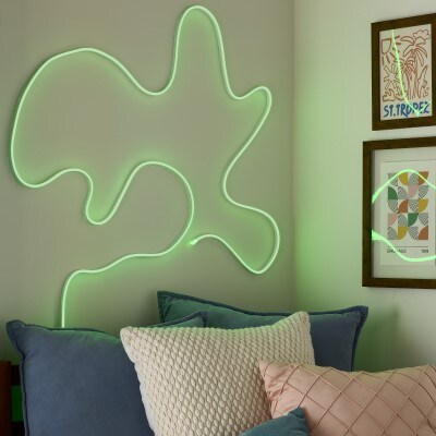 green neon LED light strip in abstract shape hung on a wall over a bed