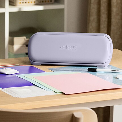 lavender cricut cutting machine with vinyl sheets on table