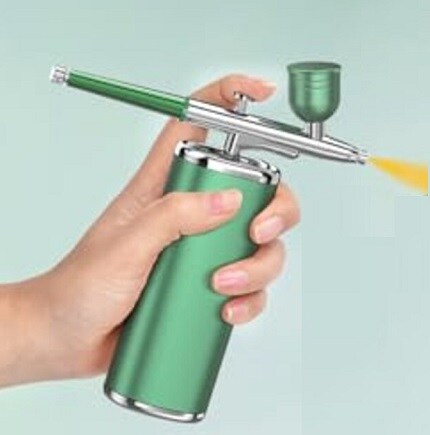 handing holding green airbrush can spraying yellow paint