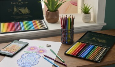 colored pencils on desk and drawing with red banner over the top of the image