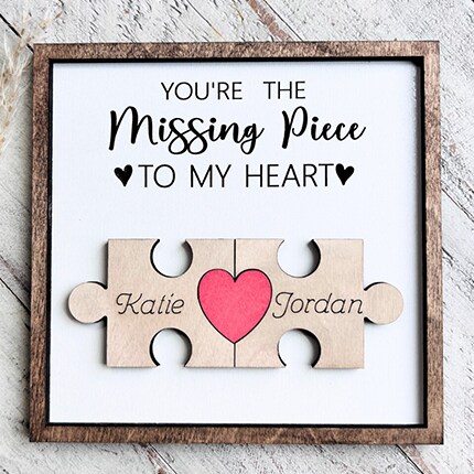 MakerPlace by Michaels A framed sign reads “You’re the missing piece to my heart,” with a pink heart joining puzzle pieces labeled Katie and Jordan, conveying loving partnership.