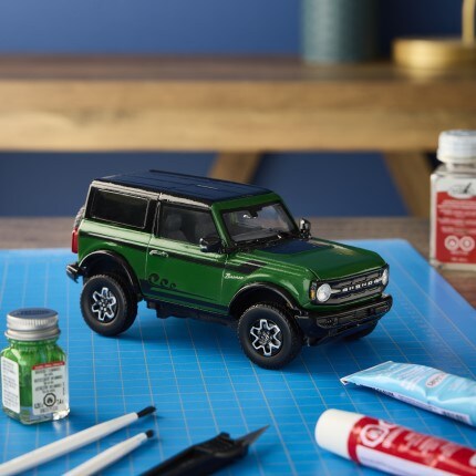 green model bronco suv on blue craft mat with assorted testor paint and accessories