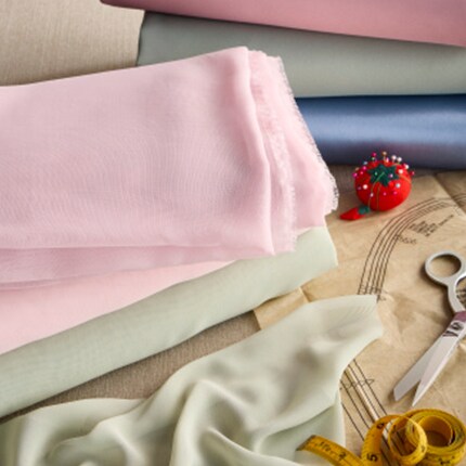 pink pastels apparel fabric on table with measuring tape and scissors 