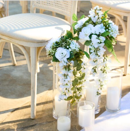 white flowers hanging on chair for wedding ceremony