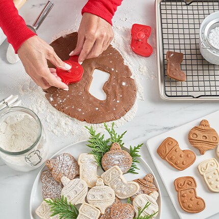 hands using cookie cutters on dough