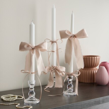 three tapered candles with tan bows on mantle