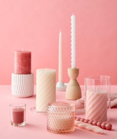Pink and white candles on a table with candle holders