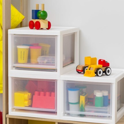 3 clear and while storage containers stacked with kids toys on top of them. 