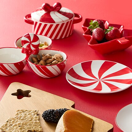 Holiday party supplies in candy cane stripes on plates and candy dishes and a Christmas Tree cutting board