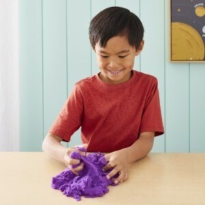 Child playing with a clump of purple sensory sand. 