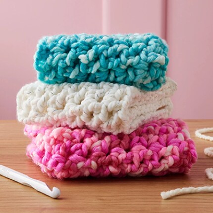 A stack of folded crochet scarves