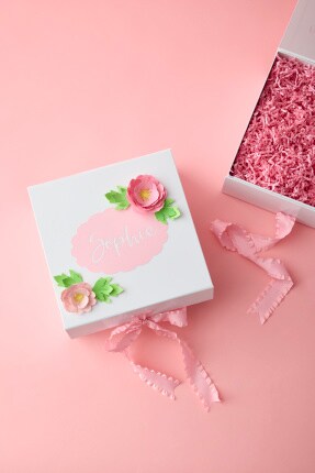 white box with pink decoration and opened box with pink crinkle stuffing