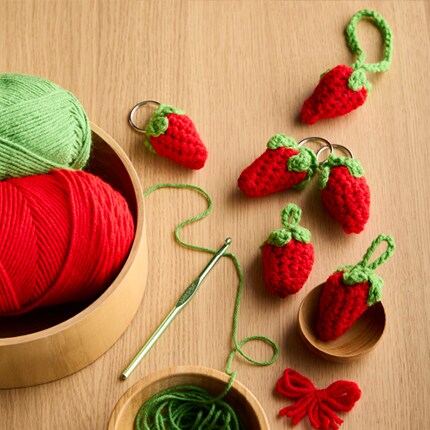 Yarn in a bowl with crochet strawberries in red and green