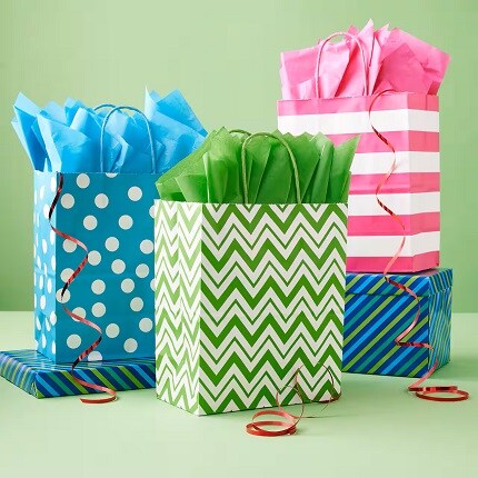 bright blue, pink and green gift bags with tissue on green background